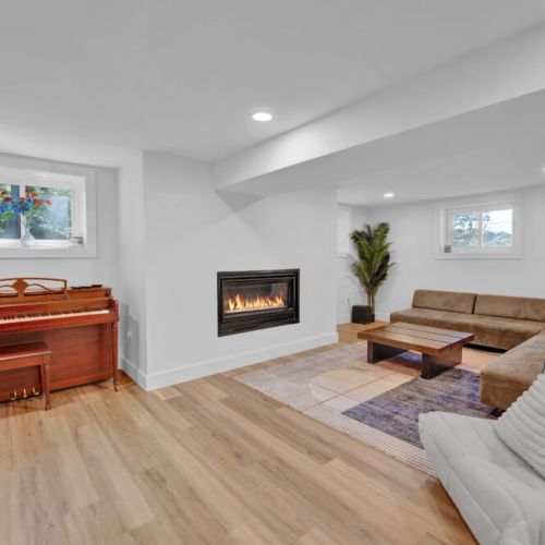 Cozy basement seating area with gas fireplace and piano.