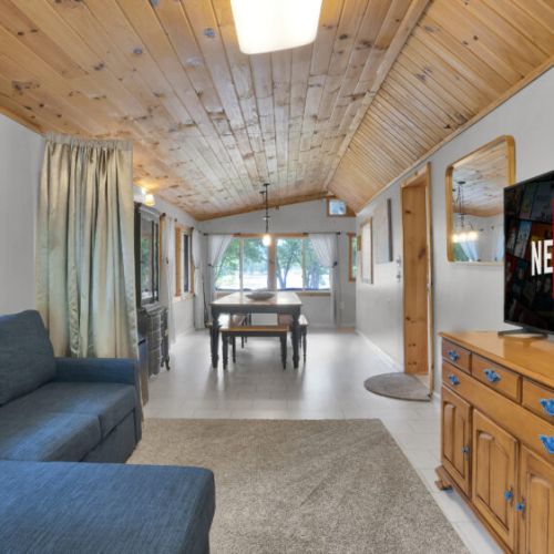 Bright and welcoming open-concept living area featuring comfortable seating, a dedicated dining space, and large windows that fill the home with natural light
