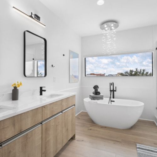 Stylish primary bathroom featuring a soaking tub, walk-in shower, double vanity, and a unique bubble-inspired light fixture for a spa-like experience.