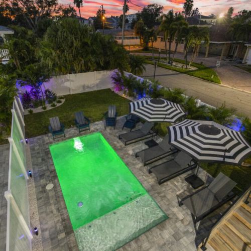 Enjoy a relaxing nighttime swim in the heated pool, illuminated by colorful lights that create a serene and inviting beachside atmosphere.