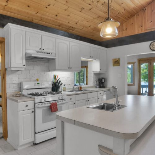 Spacious farmhouse-style kitchen featuring a marble island, white finishes, and warm natural wood details.