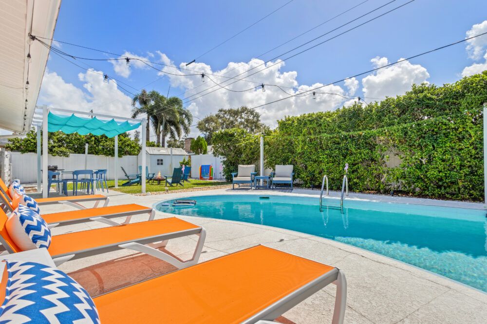 Welcome to your perfect beach getaway—this inviting backyard features a sparkling pool, spacious lounge areas, and lush greenery, creating the ideal spot to relax, soak up the sun, and start your vacation in style.