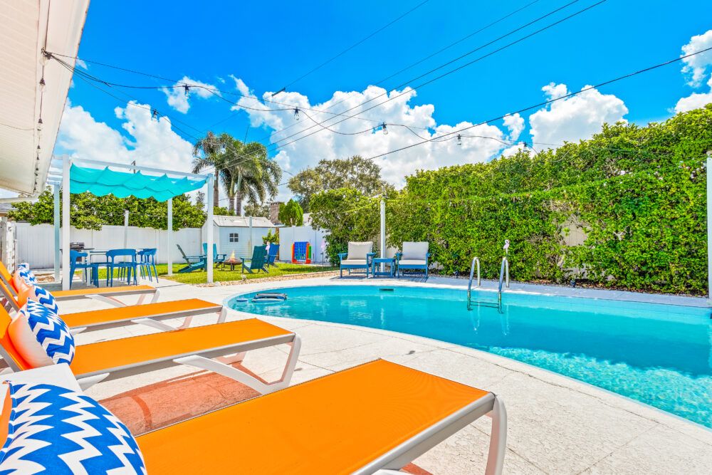 Welcome to your perfect beach getaway—this inviting backyard features a sparkling pool, spacious lounge areas, and lush greenery, creating the ideal spot to relax, soak up the sun, and start your vacation in style.