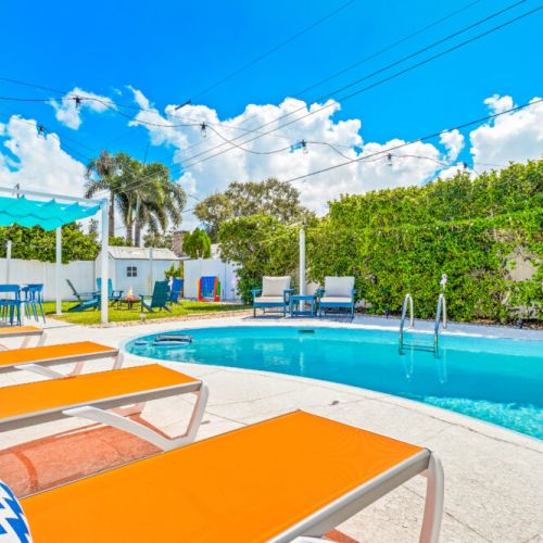 Welcome to your perfect beach getaway—this inviting backyard features a sparkling pool, spacious lounge areas, and lush greenery, creating the ideal spot to relax, soak up the sun, and start your vacation in style.