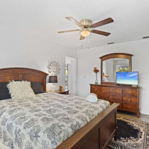 Queen bedroom, fan, tv, dresser, closet, blinds, curtains.