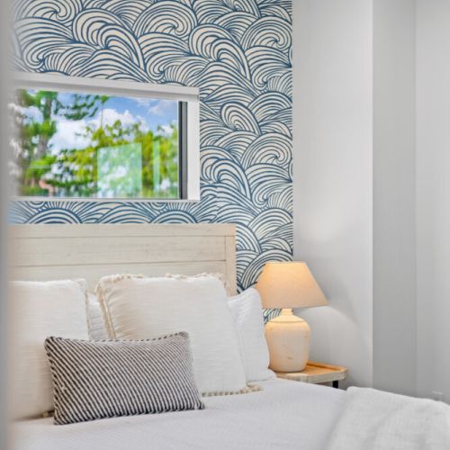 Sleep in style surrounded by vibrant, beach-inspired wallpaper that brings the coast indoors.