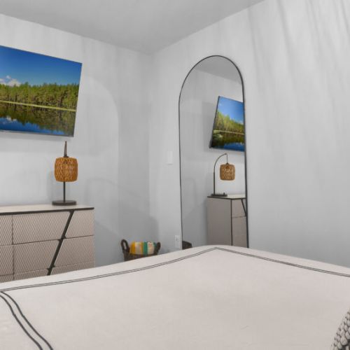 The bedroom features a mounted TV and a full-length mirror for comfort and convenience.