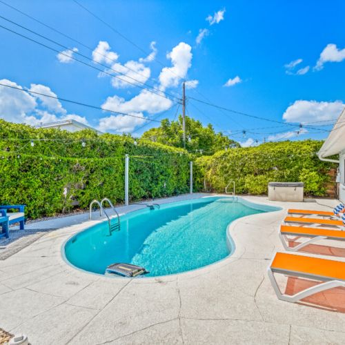Poolside seating offering the perfect spot to lounge, relax, and enjoy the sunny backyard.