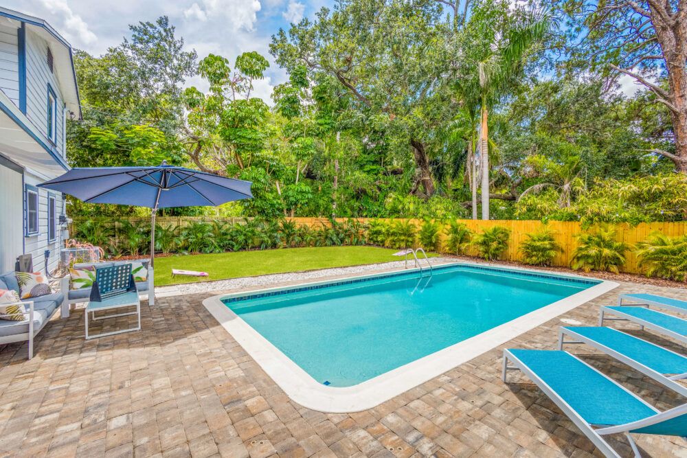 Relax in the tropical palm tree lined backyard with an outdoor sectional, pool loungers, outdoor dinning for 10 and a year round heated salt water pool.