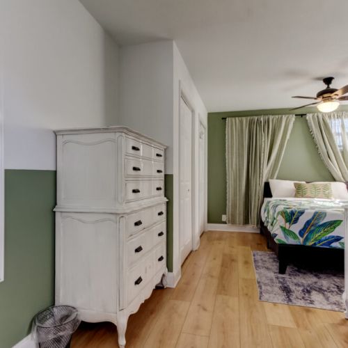 Cozy queen bedroom, dresser, fan, smart tv.