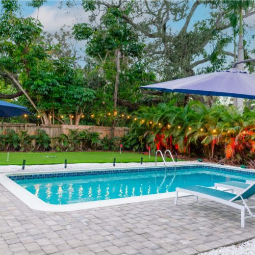 Relax in the tropical palm tree lined backyard with a 4 hole putting green, bocce court, outdoor sectional, pool loungers, outdoor dinning for 10 and a year round heated salt water pool.