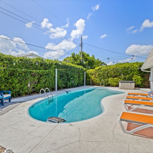 Poolside seating offering the perfect spot to lounge, relax, and enjoy the sunny backyard.