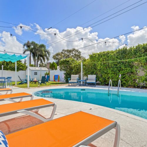 Welcome to your perfect beach getaway—this inviting backyard features a sparkling pool, spacious lounge areas, and lush greenery, creating the ideal spot to relax, soak up the sun, and start your vacation in style.