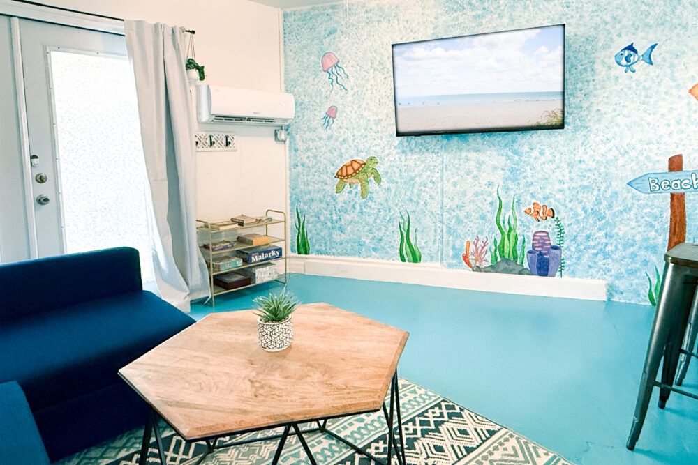 Relax in the living room enjoying the TV and hand painted seaside mural