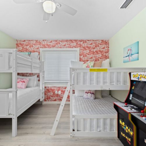 Fun-filled bedroom with two sets of bunk beds and arcade games, perfect for kids and game lovers alike.