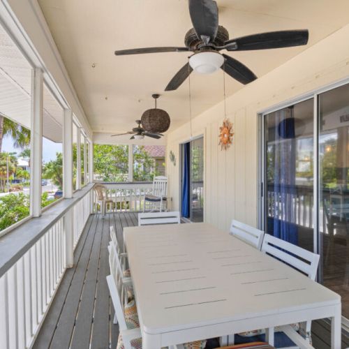 Front porch dining area with fans, located off the den and kitchen. Beautiful beach vibes.