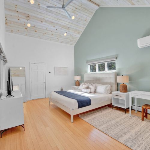 Top Floor Primary bedroom with ensuite bathroom, blackout shades, fan, tv, closet, dresser, lamps, nightstands, desk, stool, mini split.